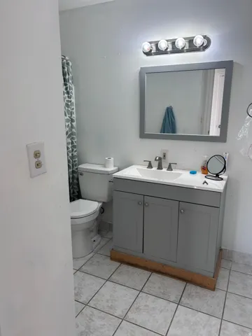 Full bath featuring vanity, light tile patterned floors, and a shower with shower curtain
