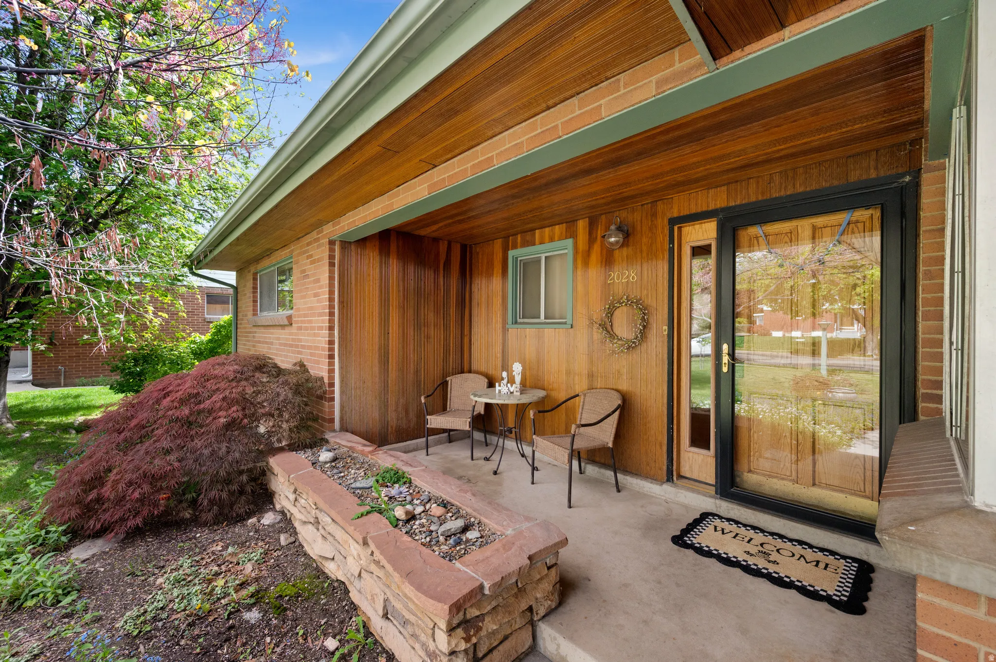 Classic mid-modern front porch with combed cedar siding and ceiling, and the original stacked-stone planter!
