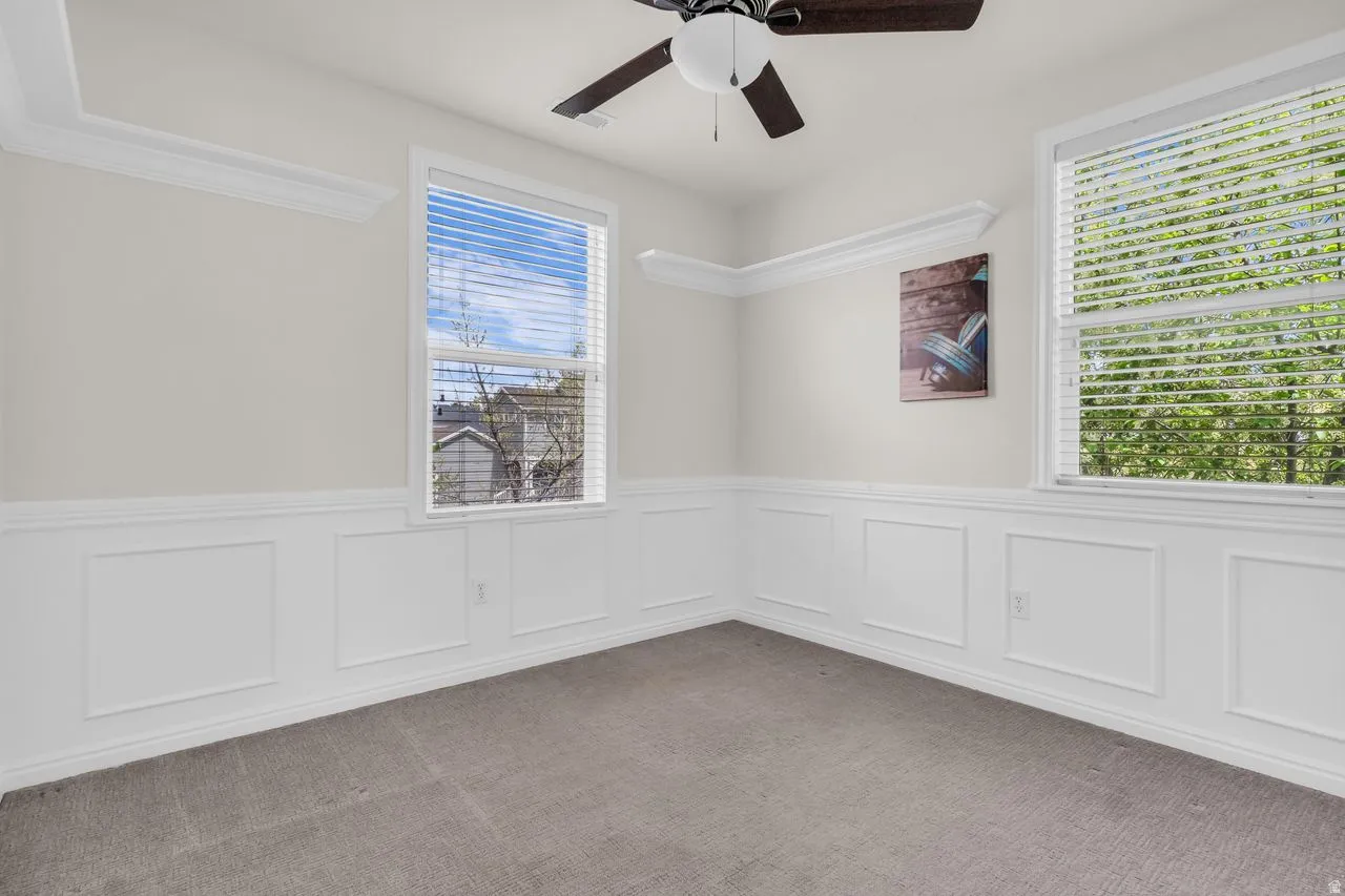 Bedroom with a ceiling fan and wainscoting