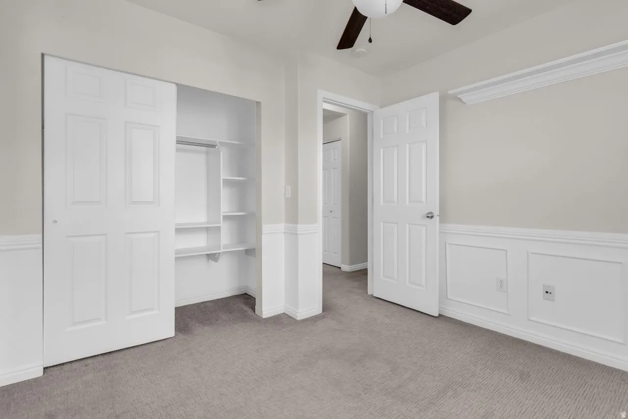 Bedroom featuring a wainscoted wall, a closet, and a ceiling fan