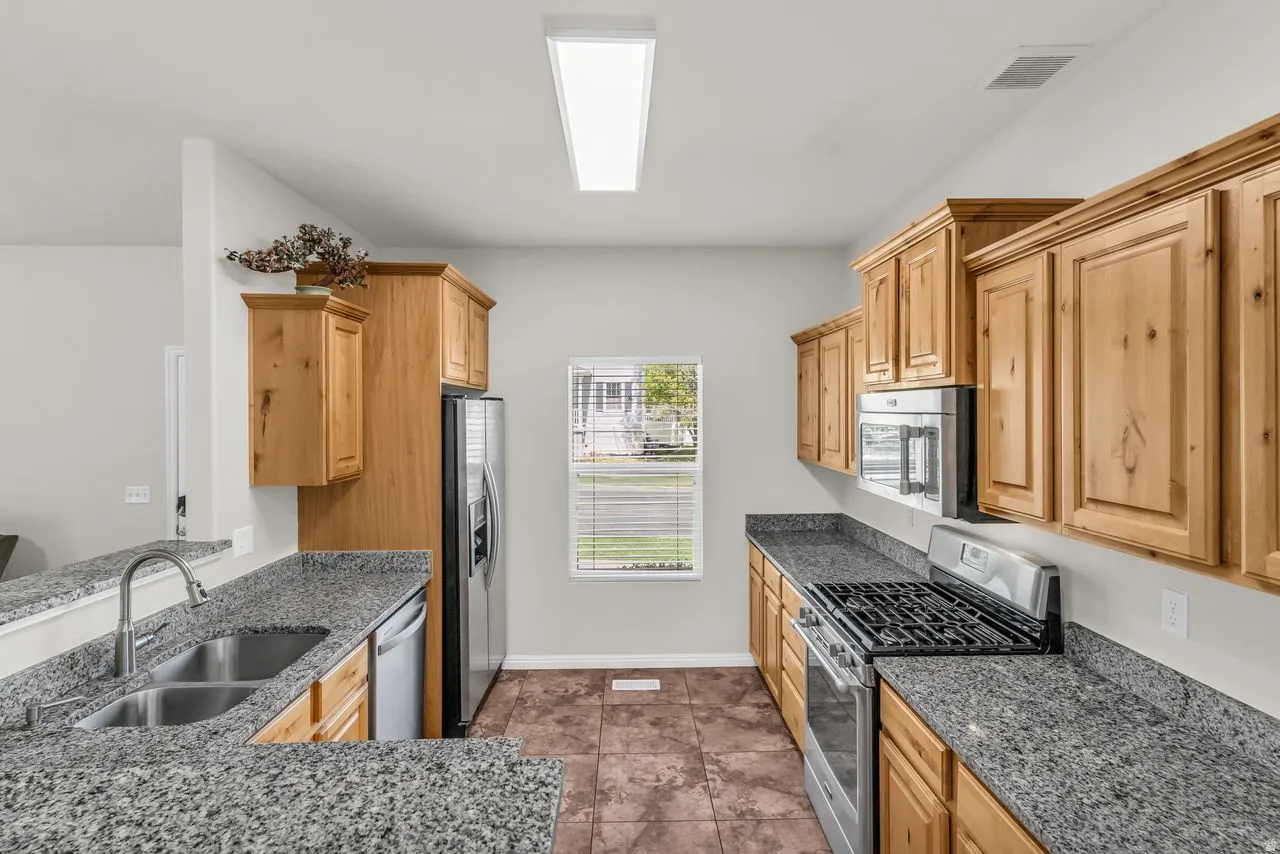 Kitchen featuring stainless steel appliances, granite countertops, and light wood finish cabinets