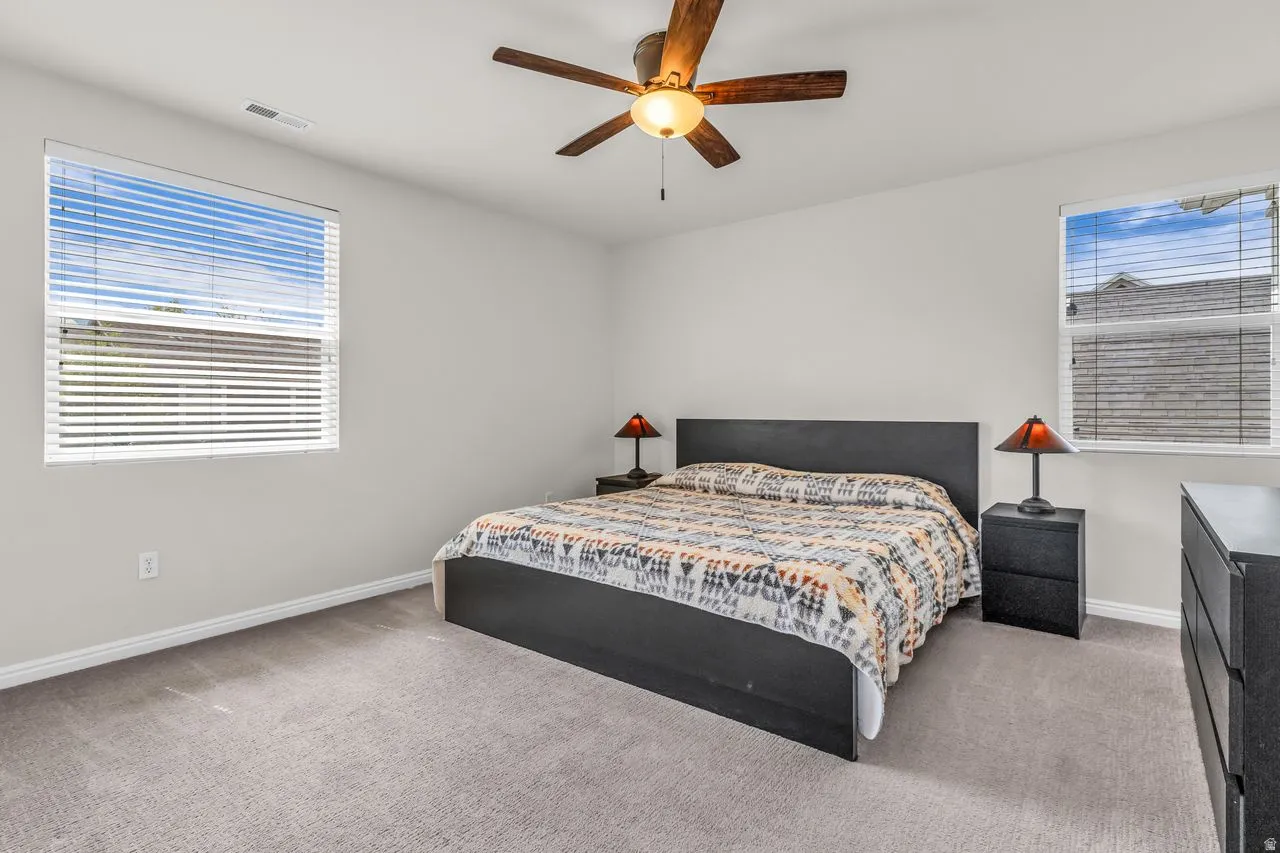 Primary bedroom featuring a ceiling fan and large windows