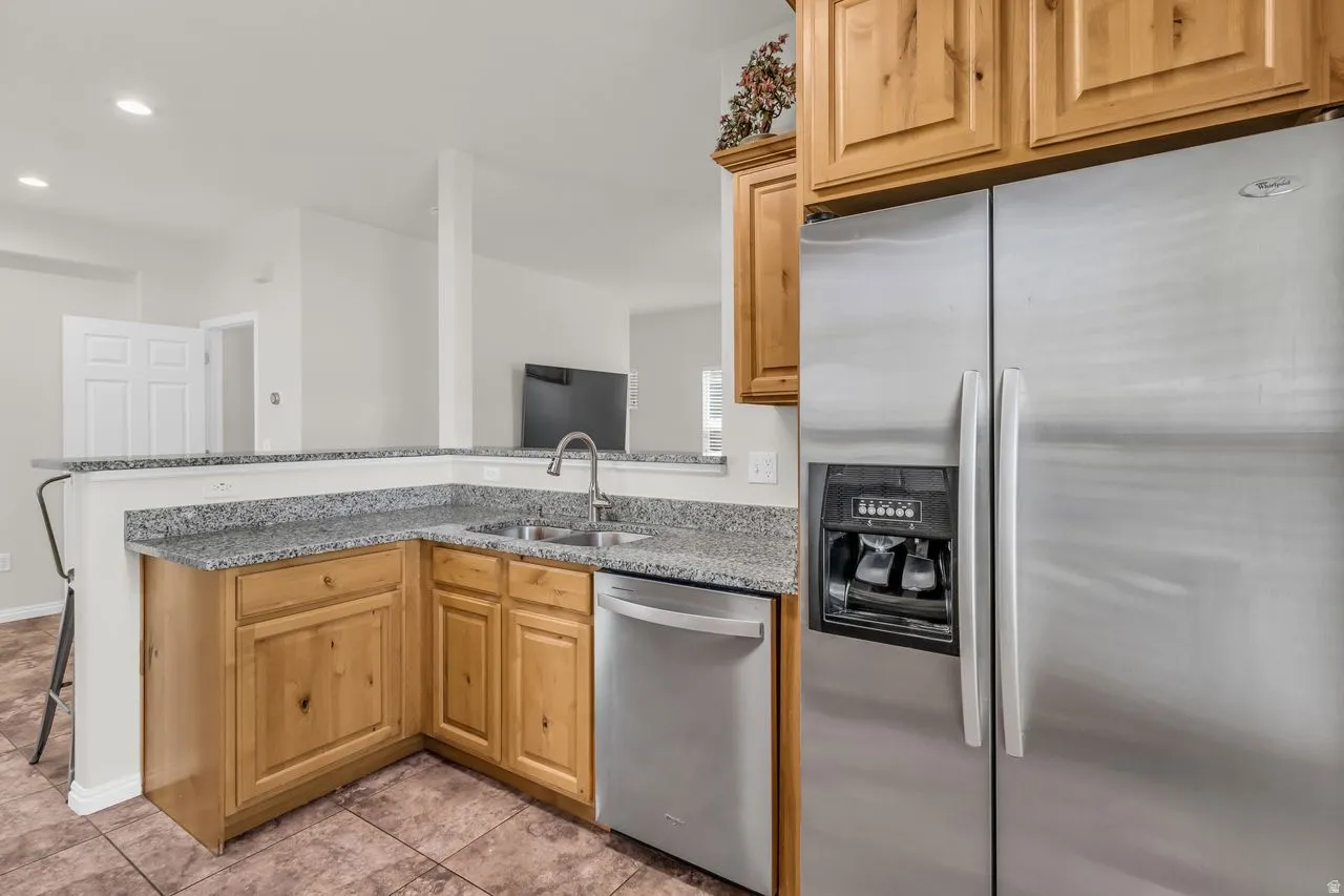 Kitchen with stainless steel appliances, granite countertops, a peninsula, tile floors, and a kitchen bar