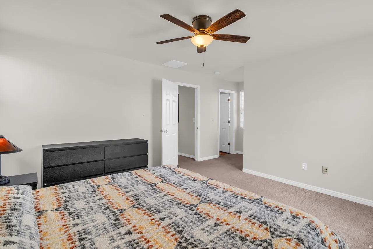 Primary bedroom with neutral colors and a ceiling fan