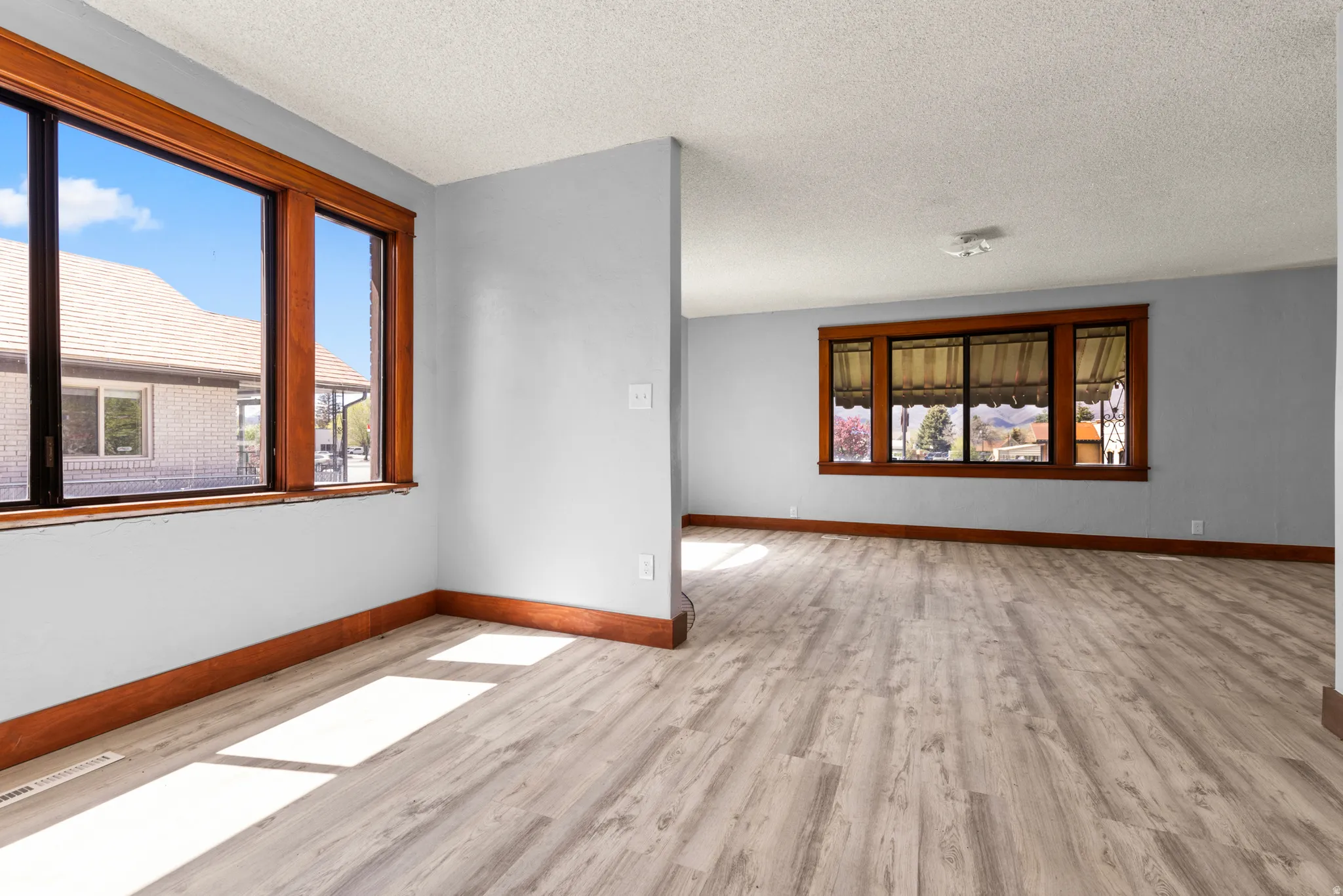 Spare room featuring light wood-type flooring, a textured ceiling, and plenty of natural light