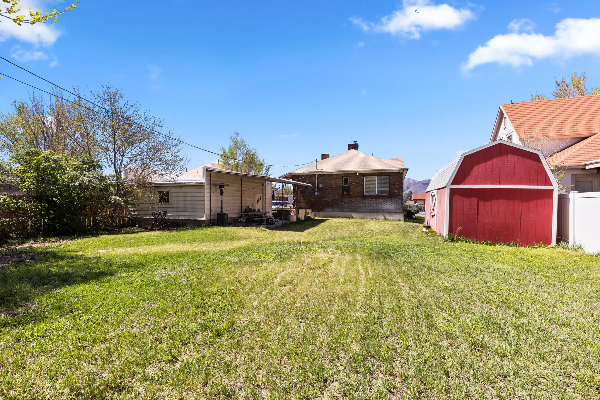 Back of house with a yard, a chimney, and a storage shed