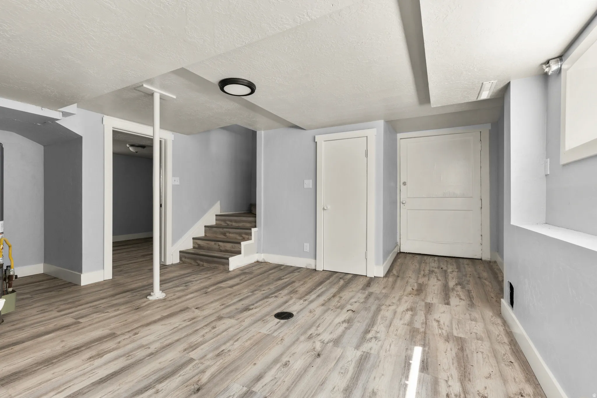 Finished basement with a textured ceiling and light wood-type flooring