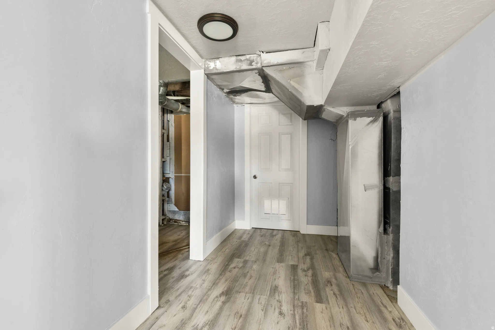 Hall with a textured ceiling and light wood-style floors