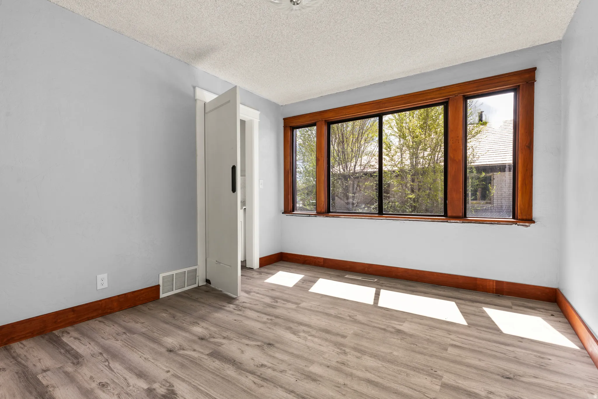 Unfurnished room featuring light wood-style floors and a textured ceiling