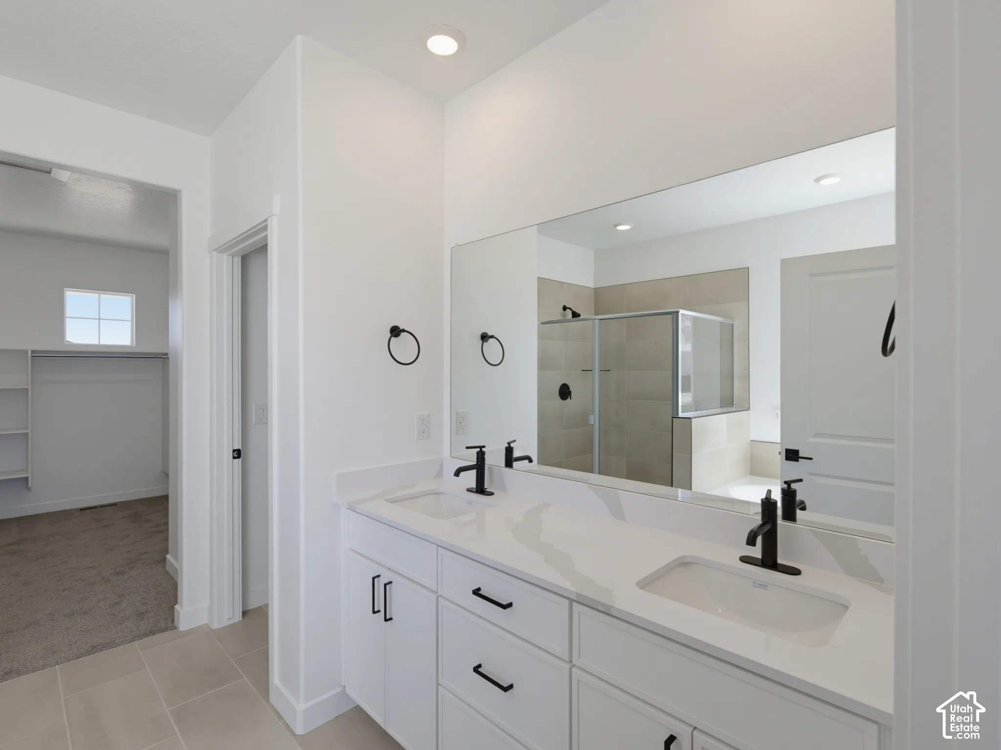 Dual vanity with white cabinetry, light-toned countertop, and matte black fixtures