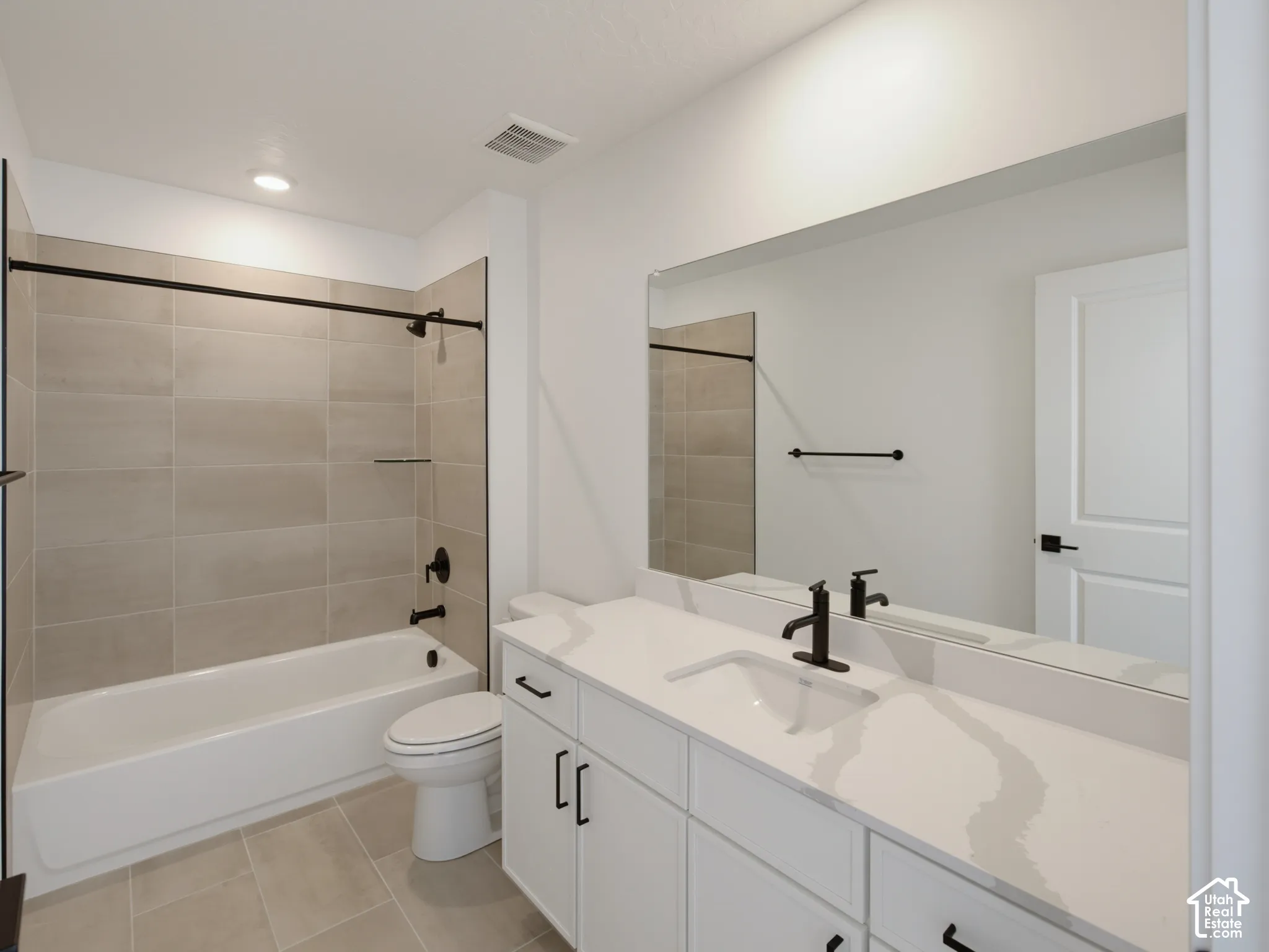 White vanity with integrated sink, black fixtures, and a large mirror