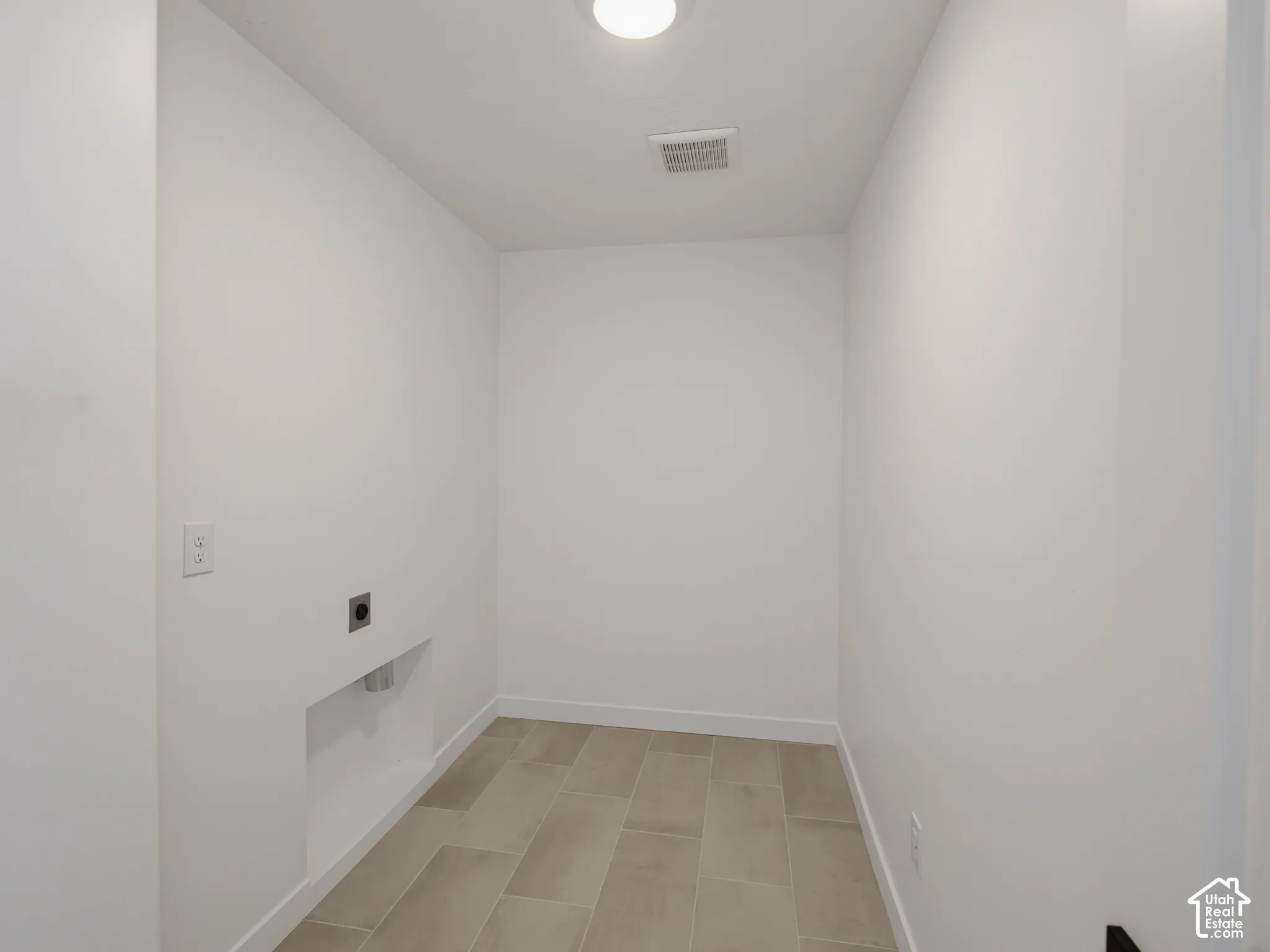 Laundry area featuring light-toned tile flooring and a ceiling-mounted light fixture