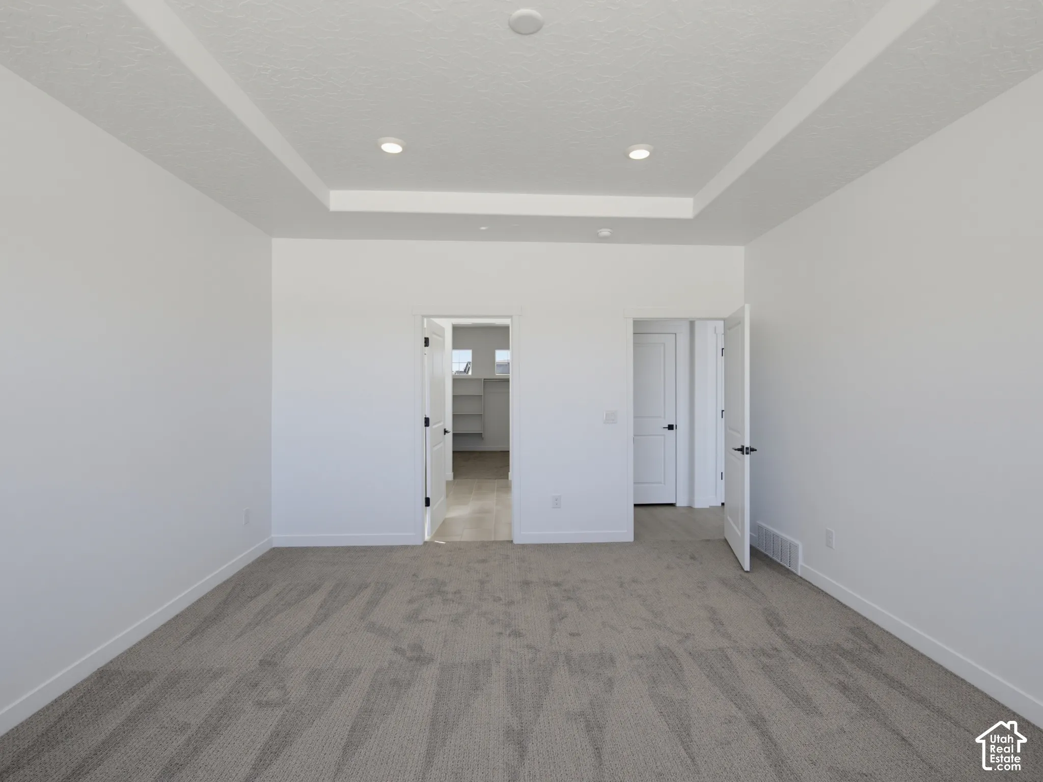 Tray ceiling with recessed lighting, carpeted flooring, and white interior doors
