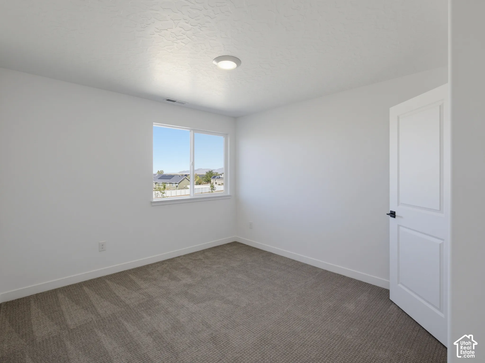 Neutral wall paint, textured ceiling, flush mount ceiling light, carpeted flooring, and a single window