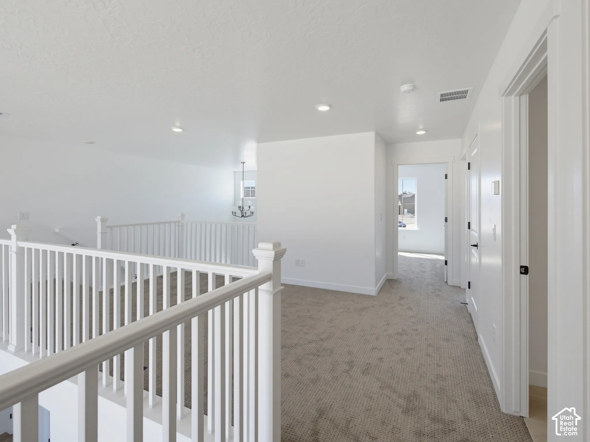 Carpeted hallway with white banister, recessed lighting, and multiple paneled doors