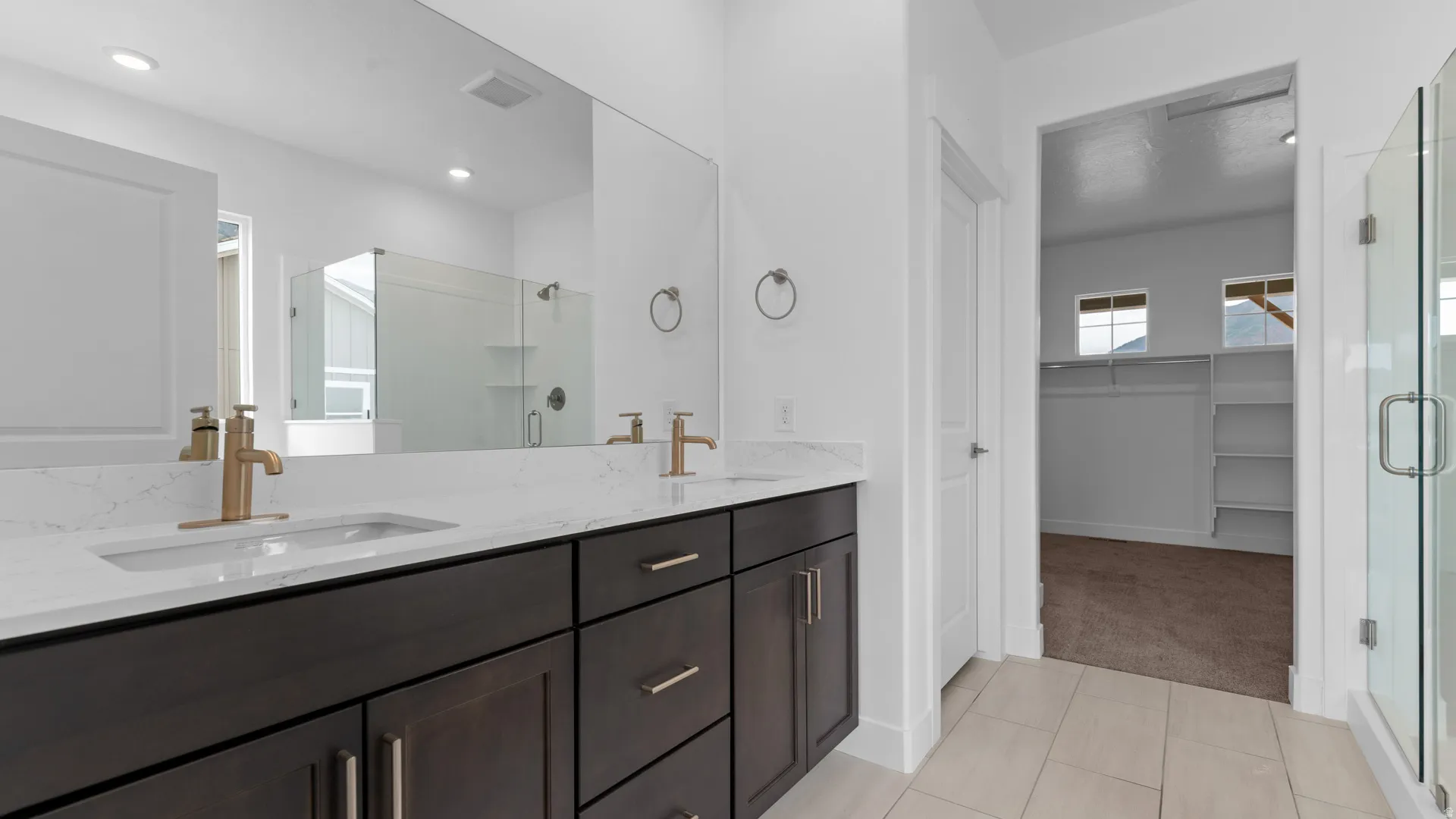 Bathroom featuring a double vanity with dark wood-finish cabinetry, white countertops, and gold-tone fixtures