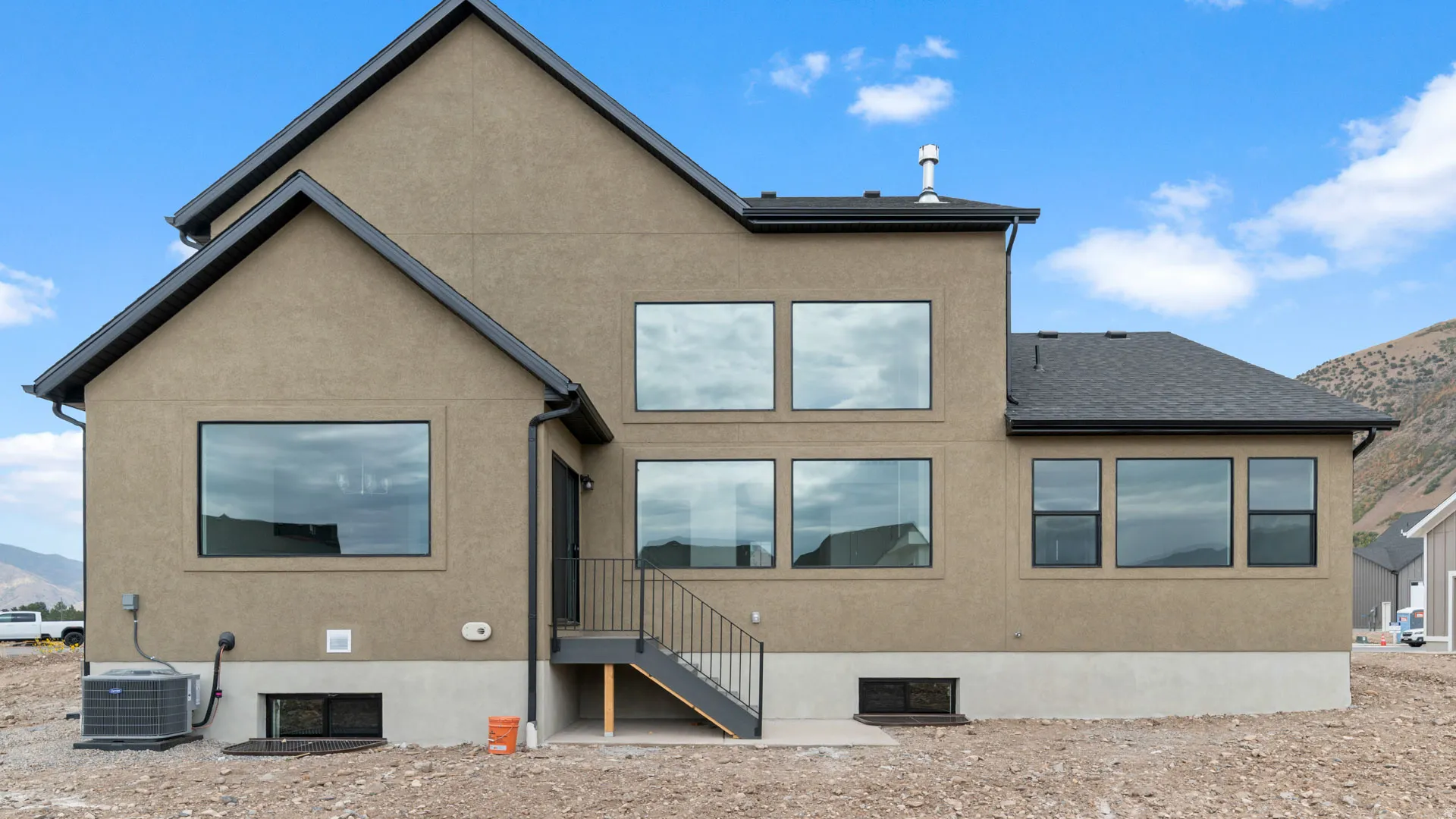Stucco exterior featuring multiple large windows and a black roof