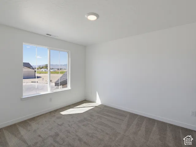 Neutral painted walls, gray carpet, and a large window with white trim, featuring recessed ceiling lighting