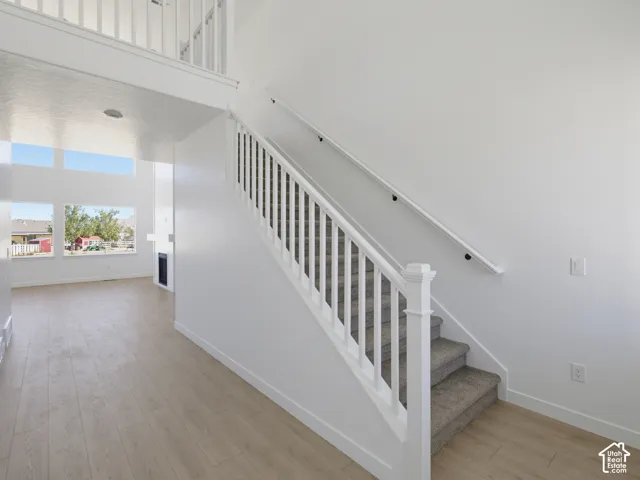 Two-story interior with a carpeted staircase, light wood-finish flooring, and white painted walls
