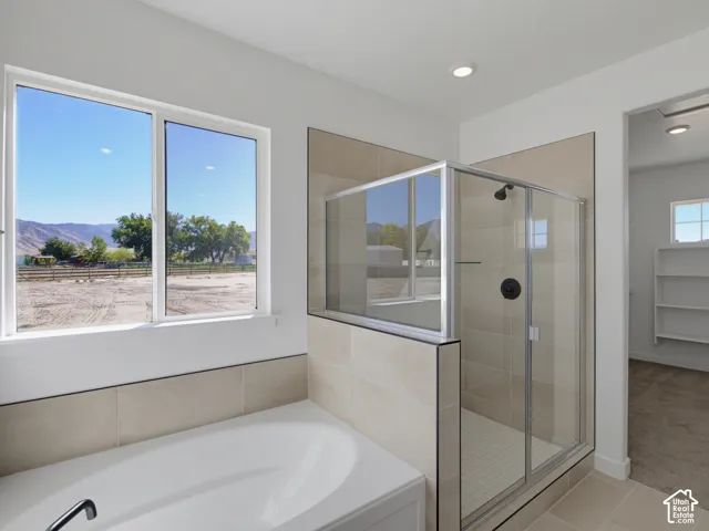Spacious bathroom featuring a built-in soaking tub, a walk-in shower with clear glass enclosure, and neutral-toned wall and floor tiling
