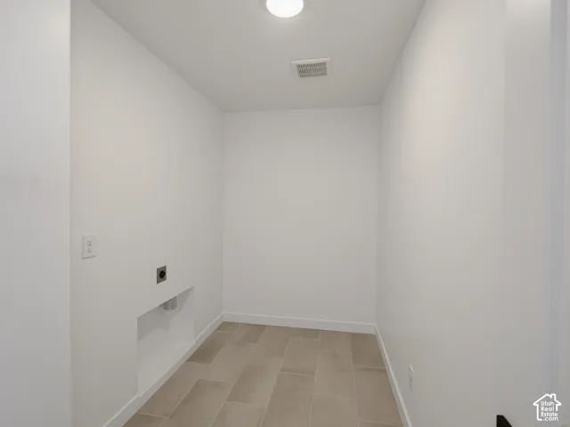 Laundry area featuring light-toned tile flooring and a ceiling-mounted light fixture
