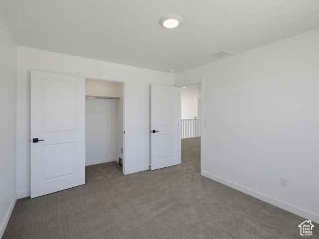 Recessed lighting, white interior doors with black hardware, and gray textured carpeting