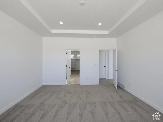 Tray ceiling with recessed lighting, carpeted flooring, and white interior doors