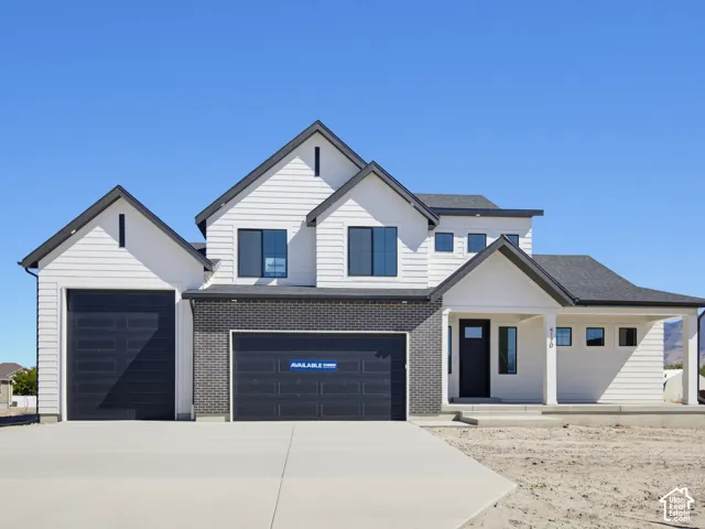 Modern exterior featuring white horizontal siding, dark brick accents, a covered entry porch, a black front door, and a two-car garage