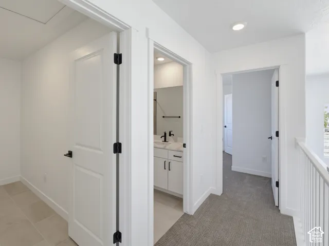 Hallway with light gray carpeting, white painted walls, and white doors with matte black hardware
