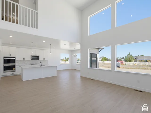 Expansive open-concept living space with high ceilings, large windows, and wood-finish flooring