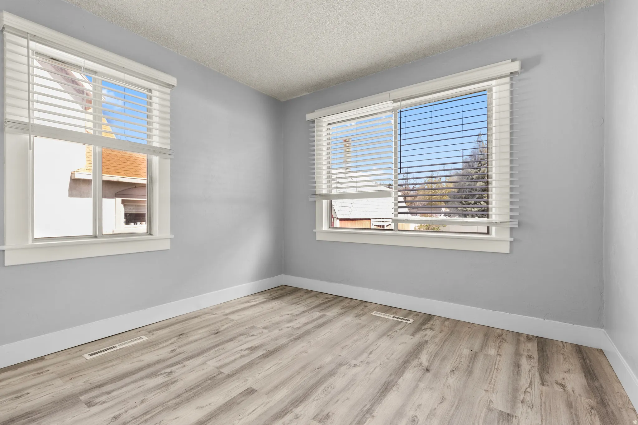 Empty room featuring a textured ceiling and light wood-style floors