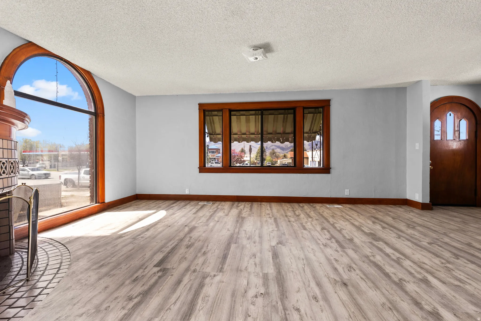 Unfurnished living room featuring light wood-style flooring, a textured ceiling, and arched walkways