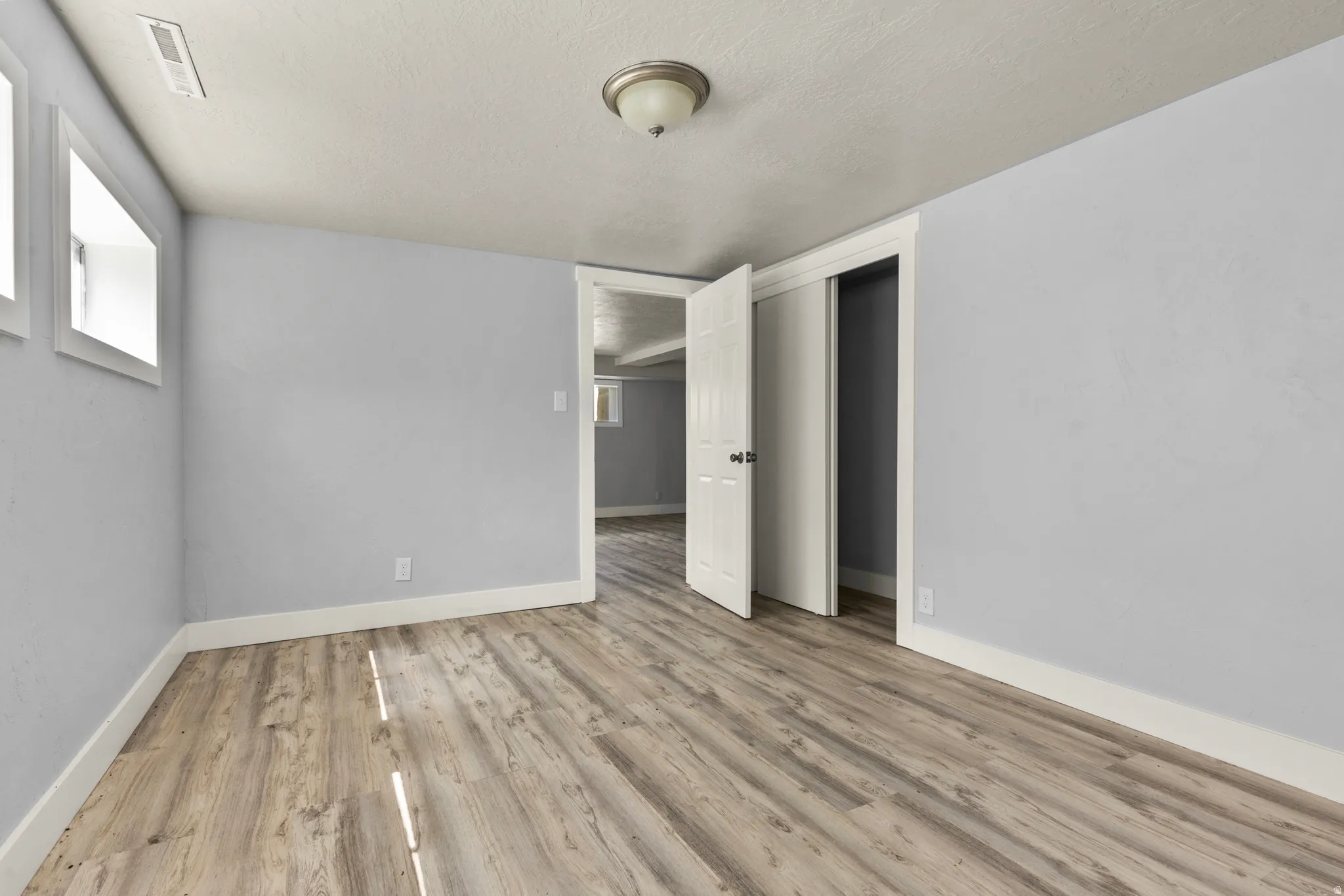 Unfurnished bedroom with light wood-style flooring, a textured ceiling, and a closet