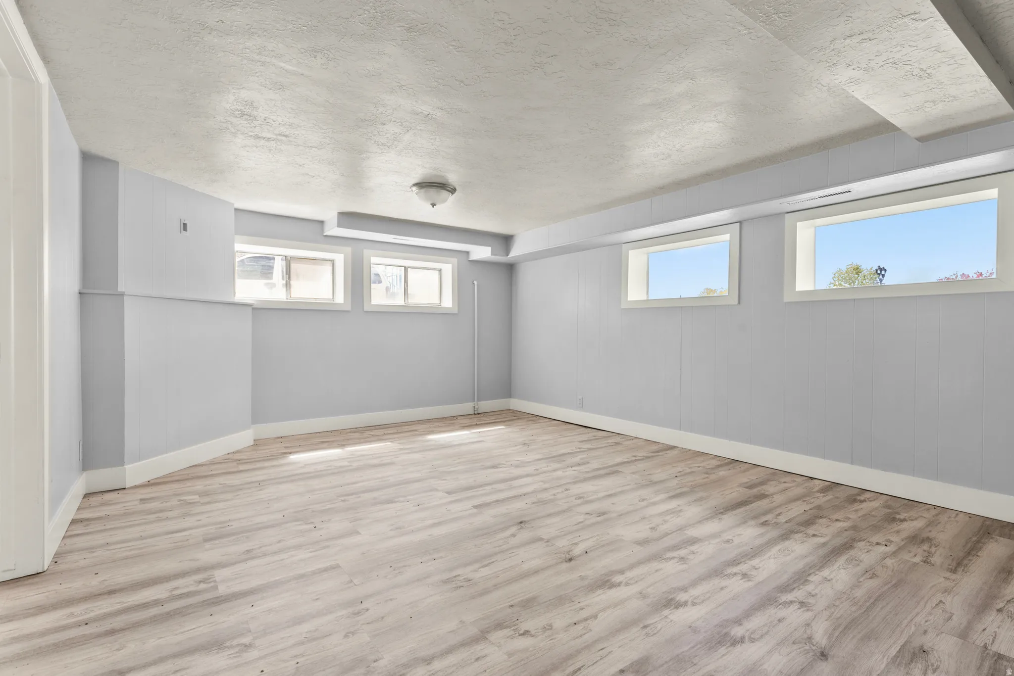 Basement with a textured ceiling and light wood-style flooring