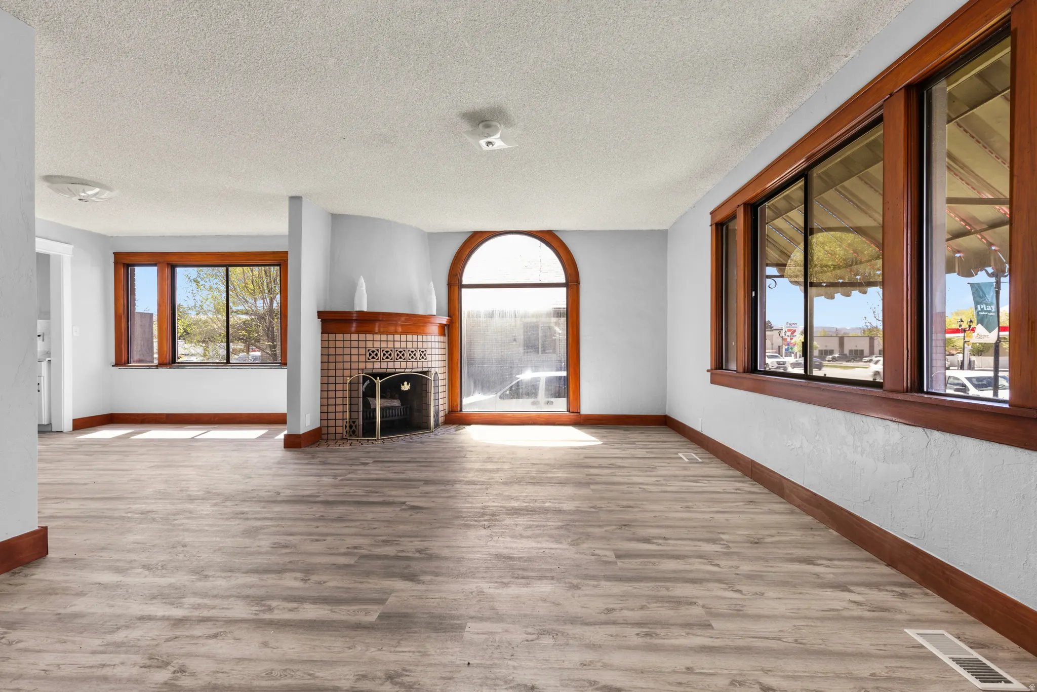 Unfurnished living room with light wood-type flooring, a textured ceiling, and a tiled fireplace