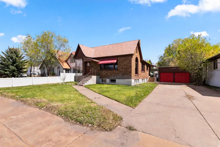 View of front of house with a detached garage, an outbuilding, and a tiled roof