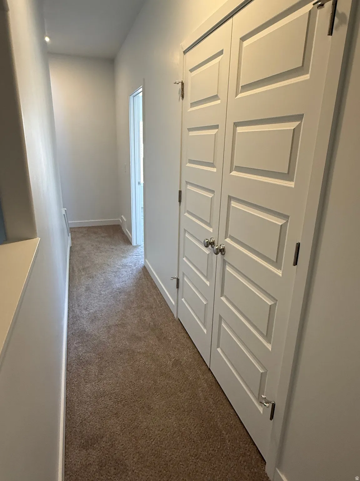 Hall featuring dark carpet and baseboards