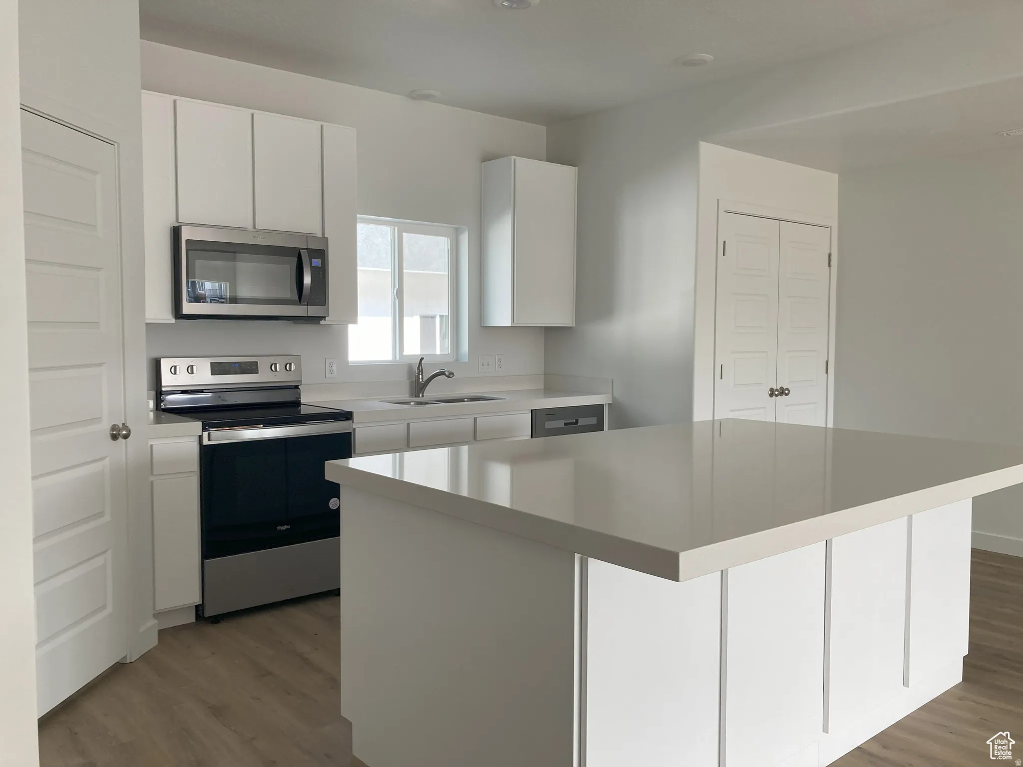 Kitchen with stainless steel appliances, white cabinets, a kitchen island, and dark wood-style floors