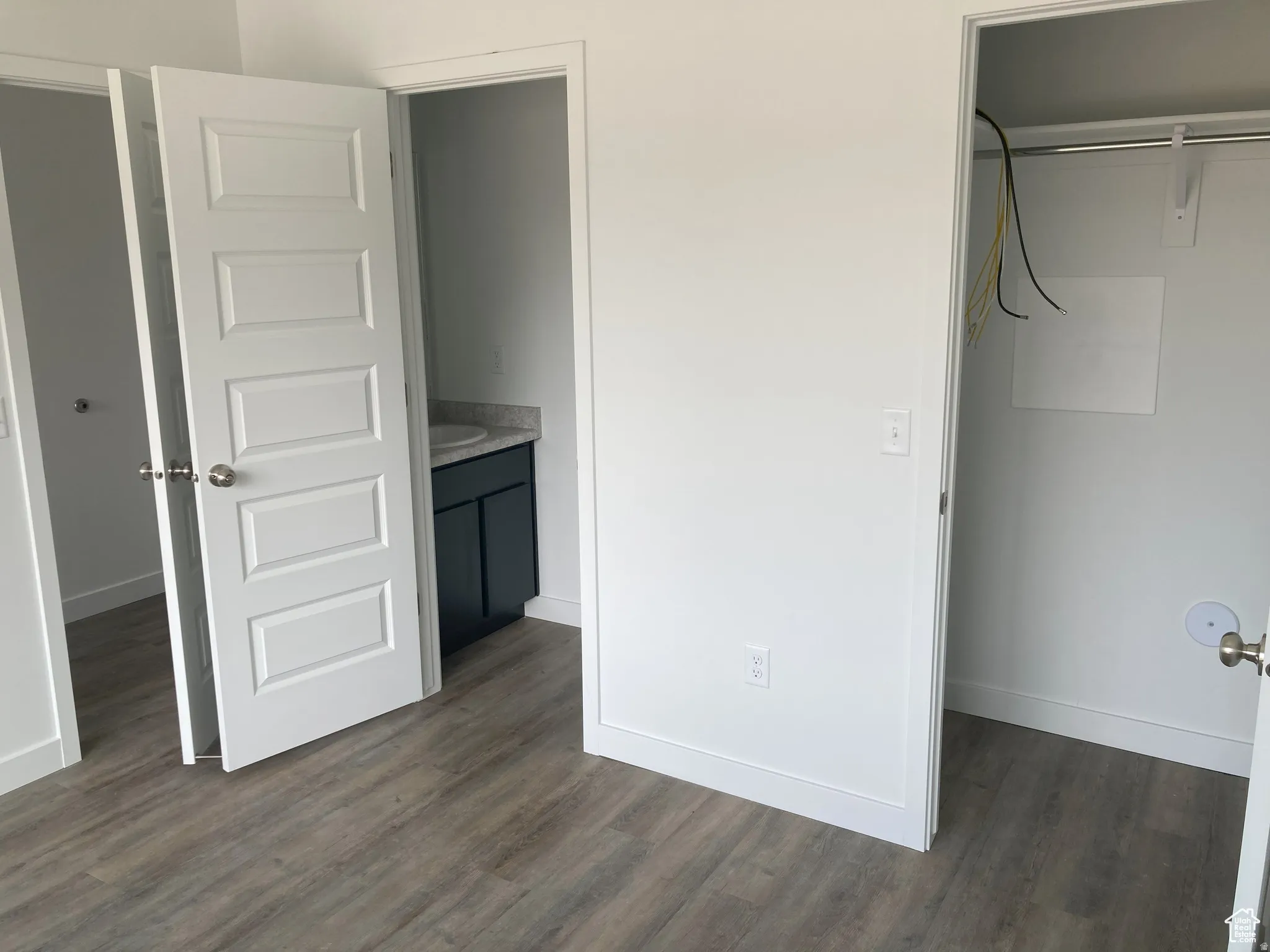Unfurnished bedroom with dark wood-type flooring and connected bathroom