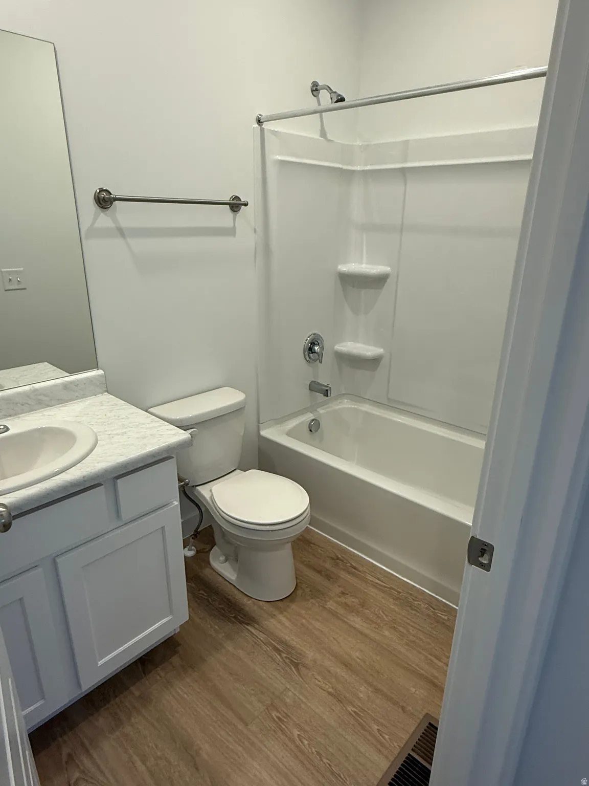 Bathroom featuring vanity, dark wood-style flooring, and shower / tub combination