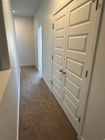 Hall featuring dark carpet and baseboards