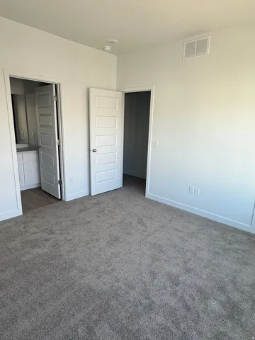 Unfurnished bedroom featuring dark colored carpet and ensuite bathroom