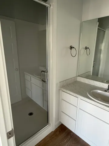Bathroom featuring vanity, a shower stall, and dark wood-style flooring