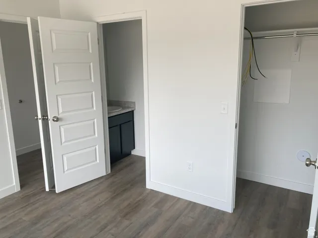 Unfurnished bedroom with dark wood-type flooring and connected bathroom