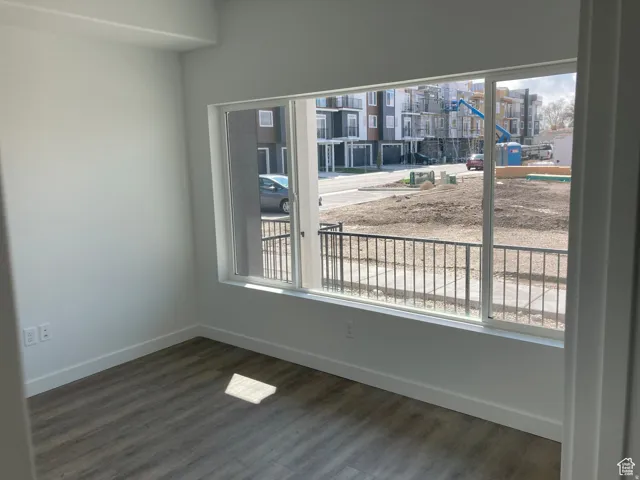 Unfurnished room featuring baseboards and dark wood-style flooring