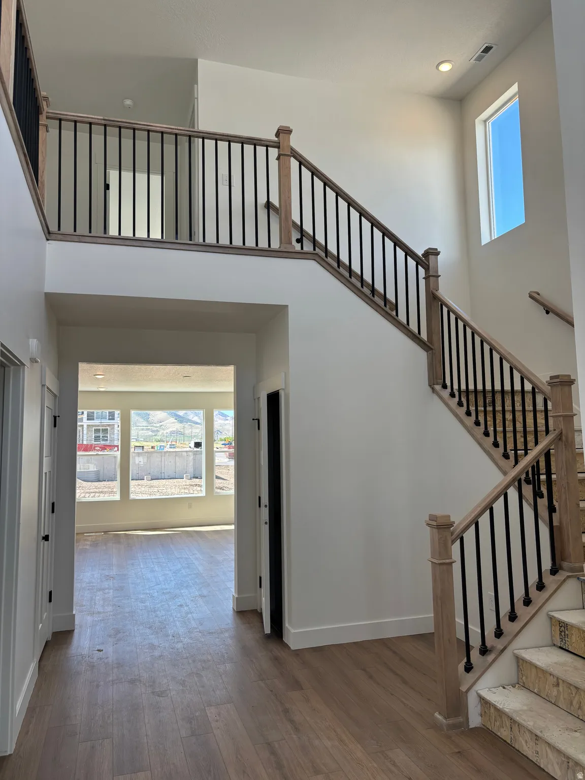Stairs with plenty of natural light, a high ceiling, hardwood / wood-style flooring, and recessed lighting