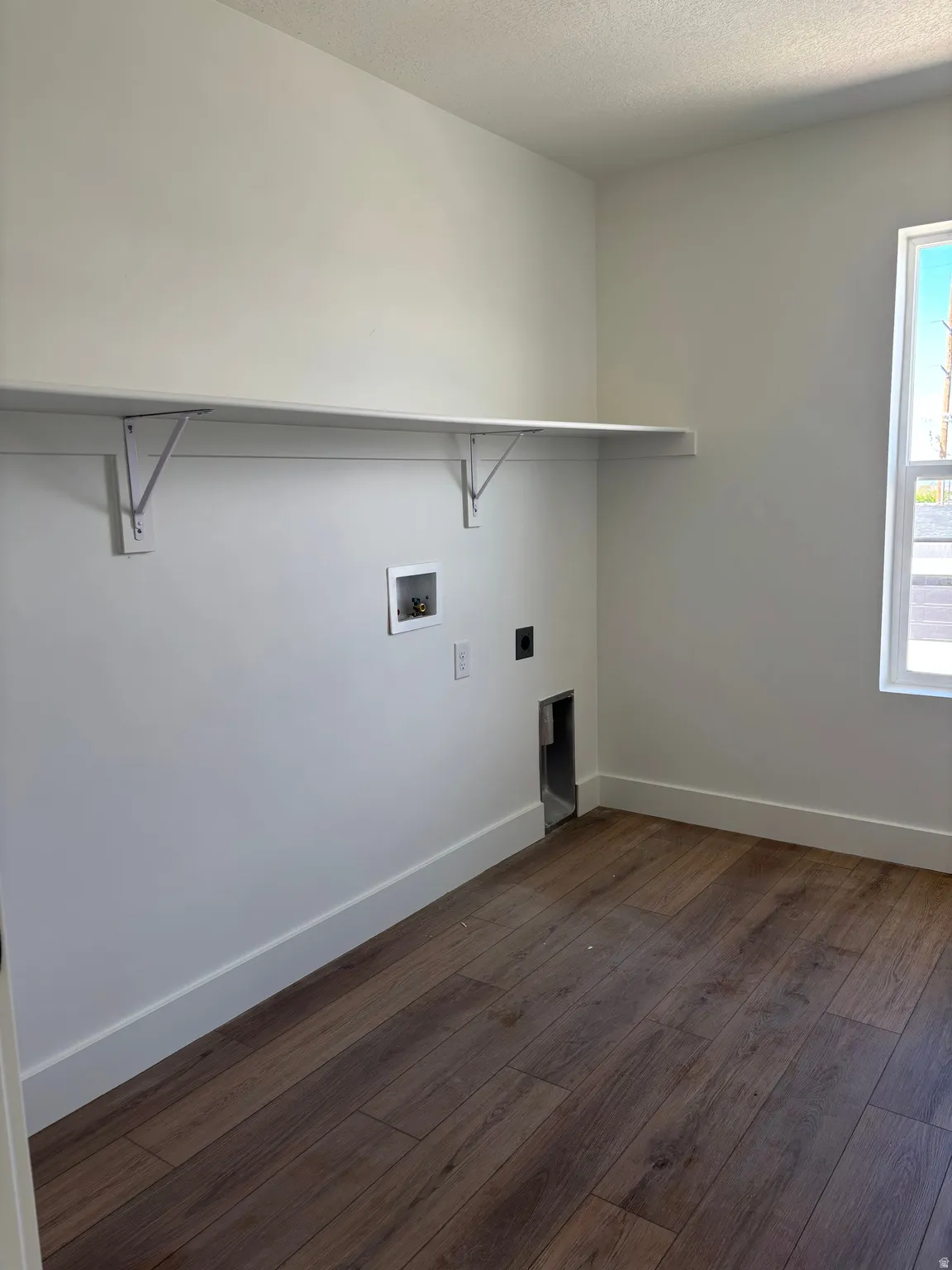 Laundry area featuring dark wood finished floors, hookup for a washing machine, a textured ceiling, and hookup for an electric dryer