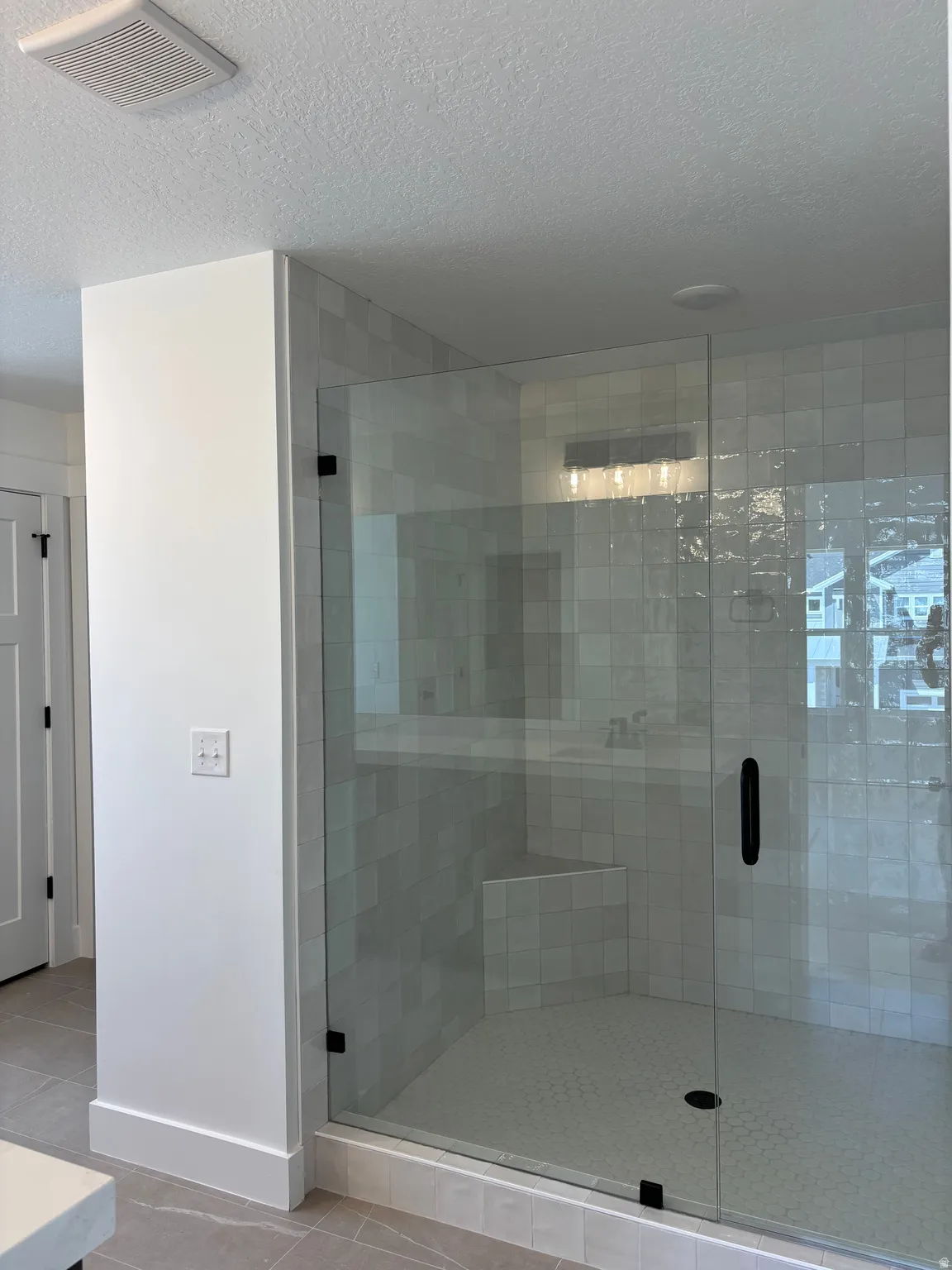 Bathroom with a textured ceiling, a stall shower, light tile patterned flooring, and vanity