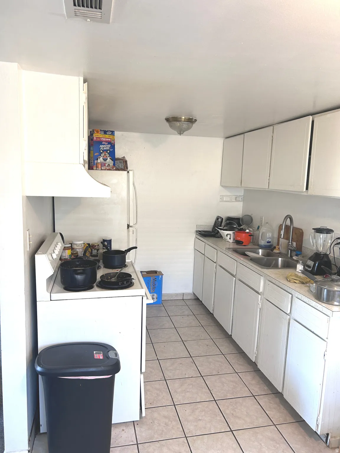 Kitchen featuring white appliances, light countertops, white cabinets, and light tile patterned floors