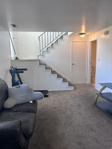 Carpeted living area featuring stairs